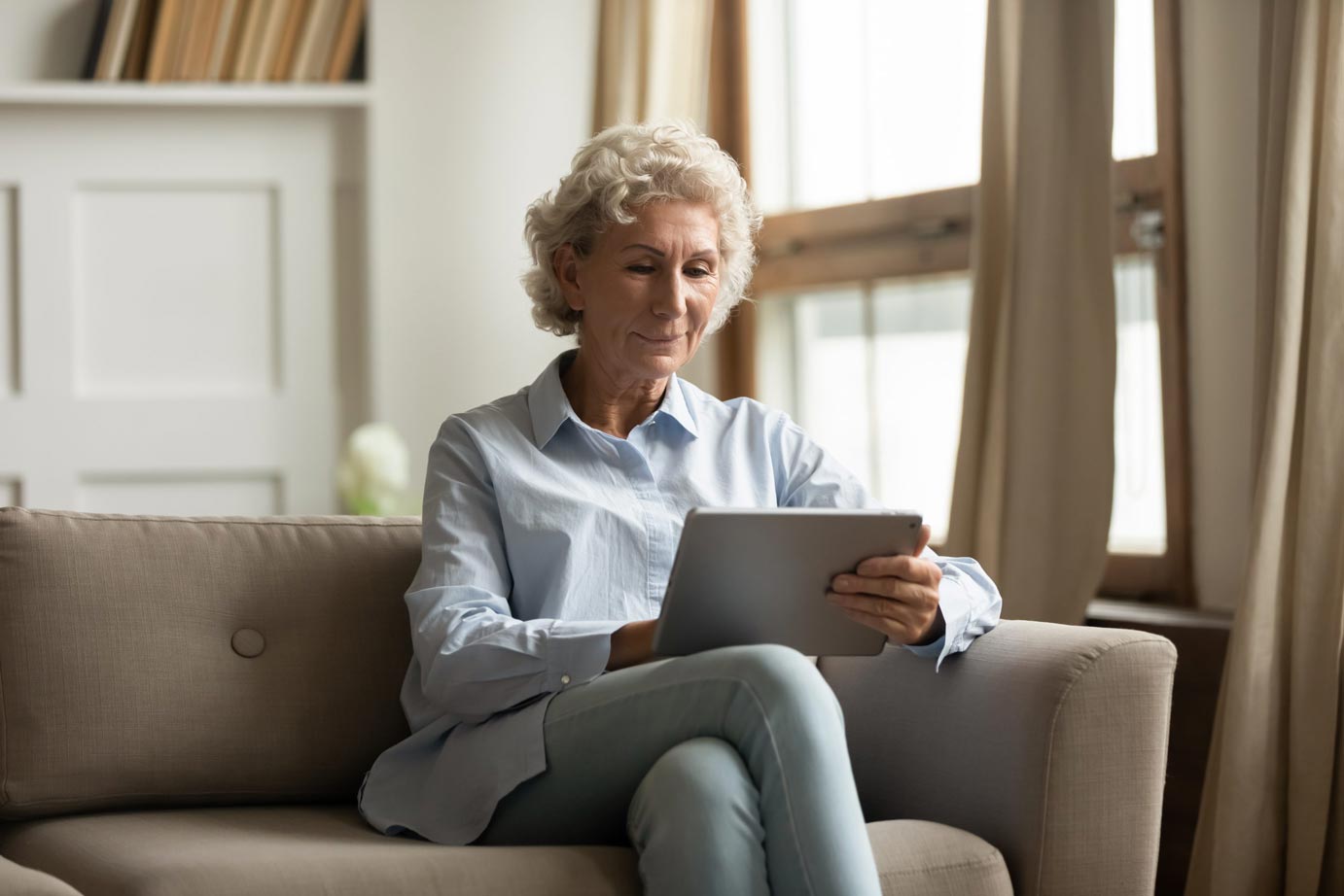 Peaceful pleasant senior woman using digital tablet pc indoors