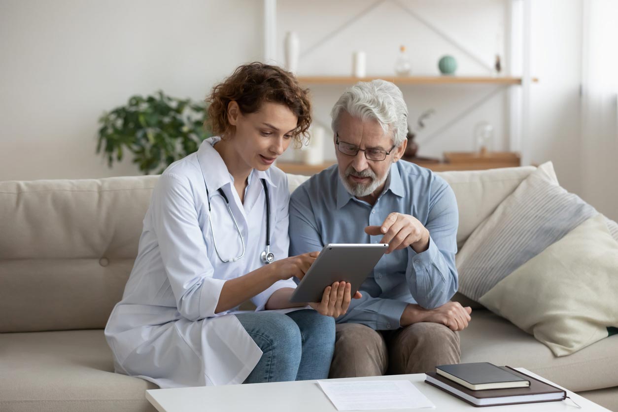 Female doctor using digital tablet consulting senior patient at home